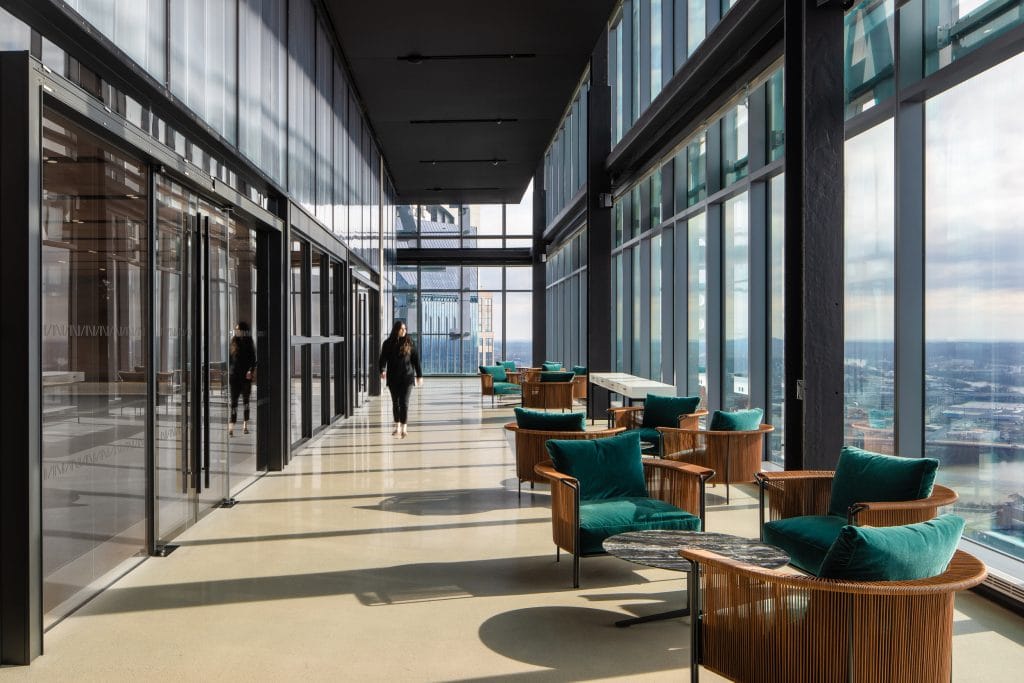 Alliance Bernstein 6 Modern office lounge with floor-to-ceiling windows, teal chairs, and bright natural light.