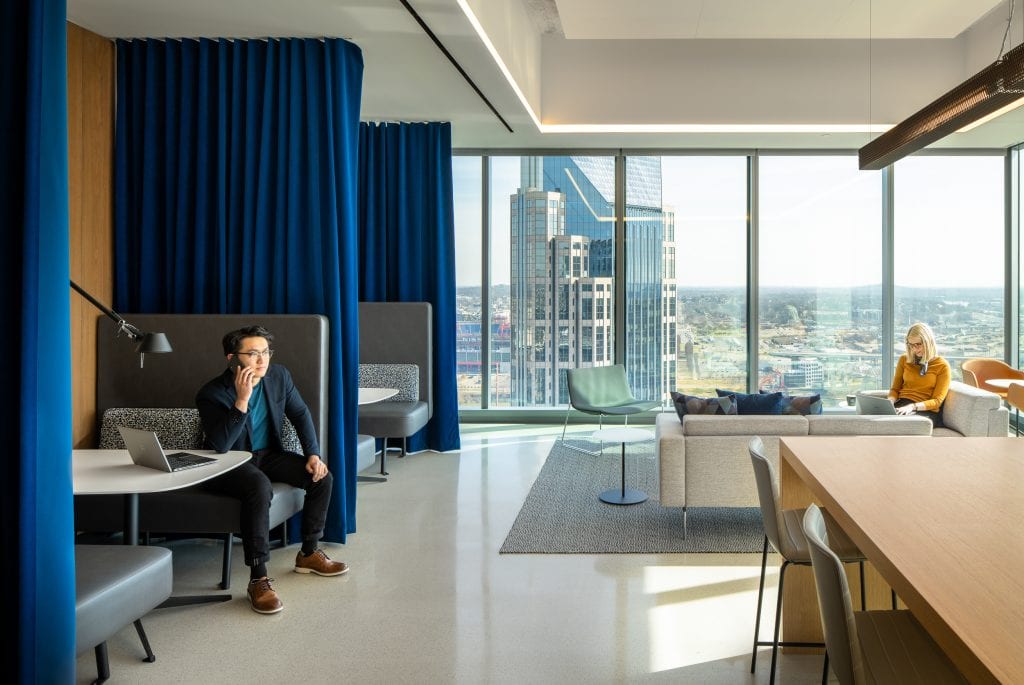 Alliance Bernstein 20 Lounge space featuring casual seating, blue curtains, and city views through large windows in Nashville, TN.