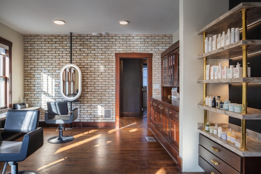 Bangarang 6 Hair salon interior with brick wall, wooden cabinets, and styling chairs.