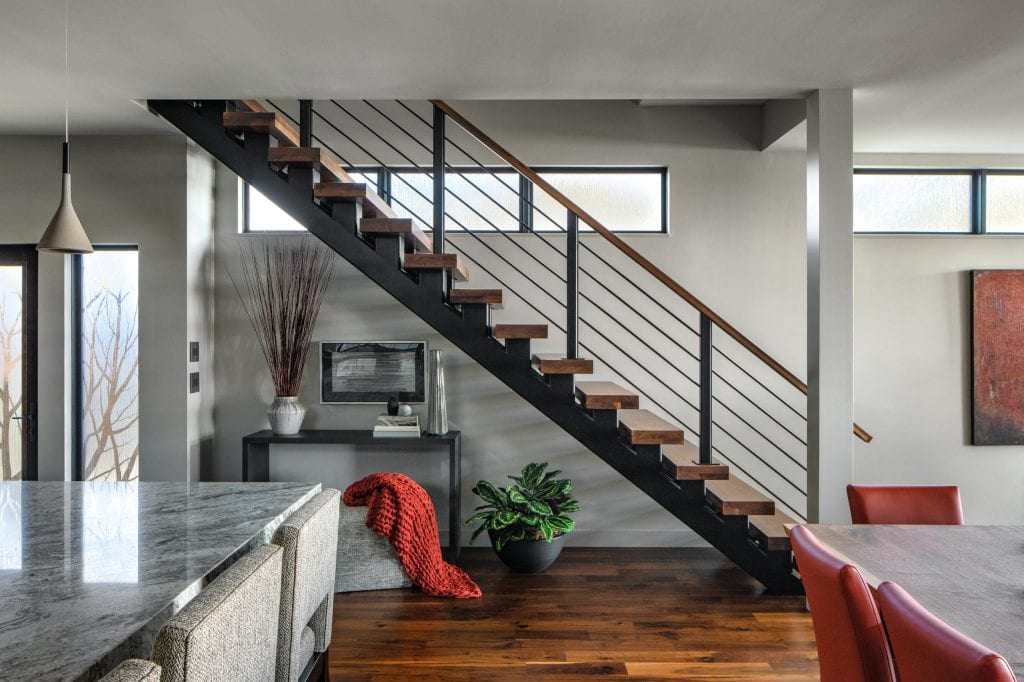 LAKESIDE CONTEMPORARY 6 Floating staircase with wooden steps and black railing in a modern home.