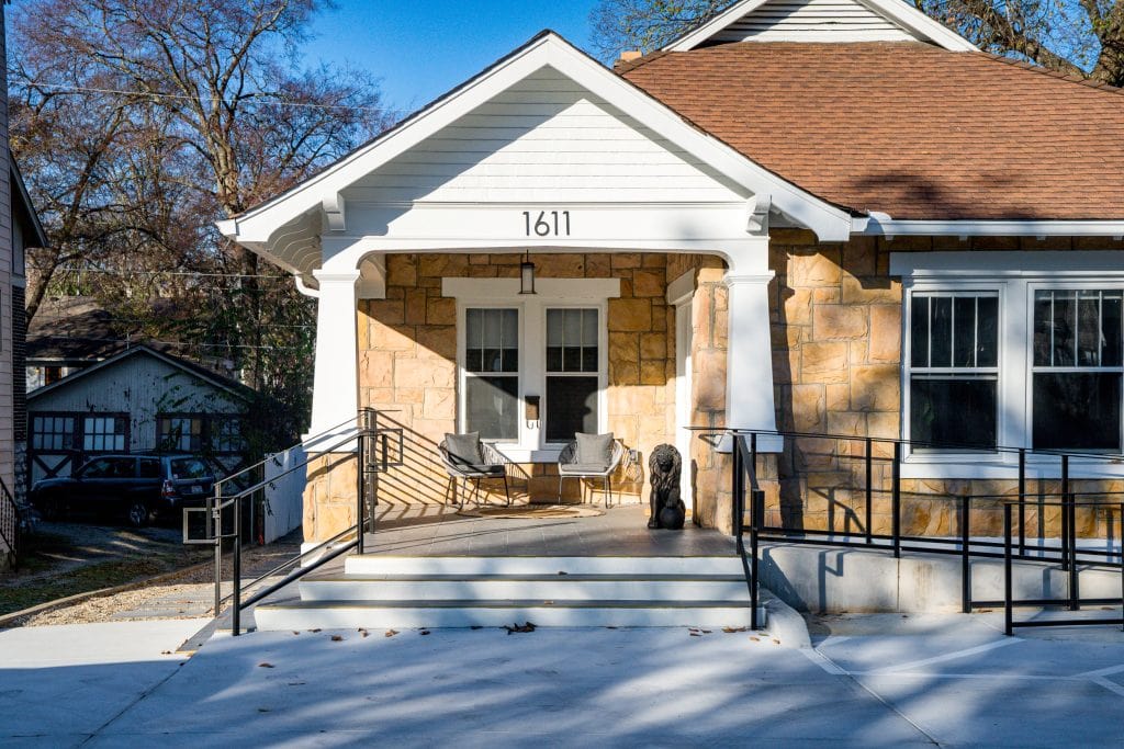 Bangarang 2 Front porch of a historic building renovation with stone facade and modern seating.