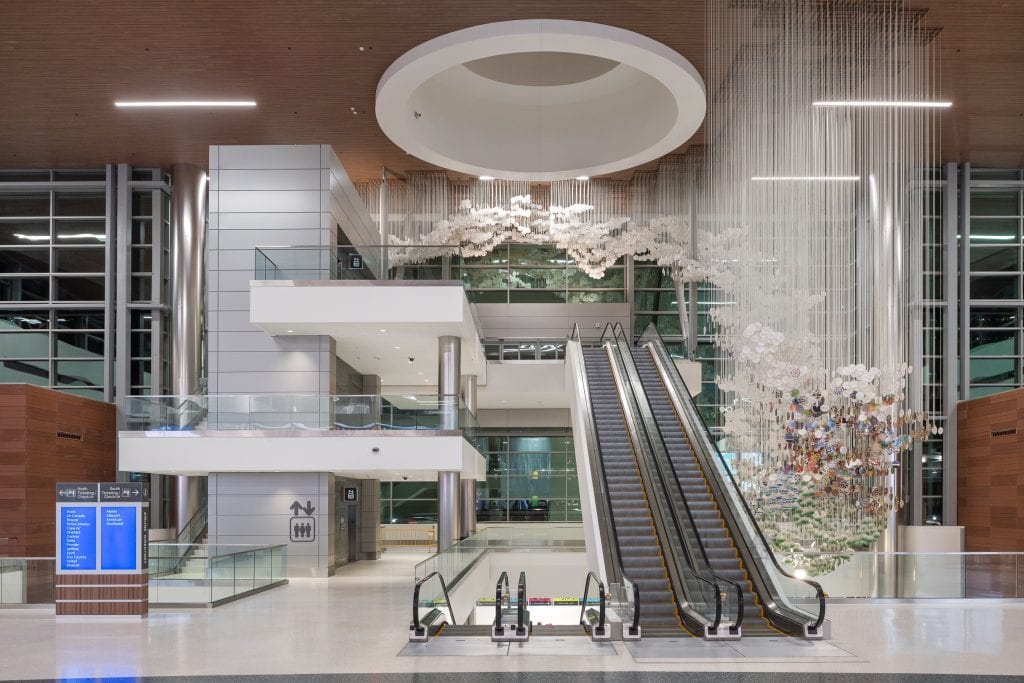 BNA - Nashville Airport 12 Night view of the terminal interior at Nashville International Airport featuring escalators and a suspended sculpture.