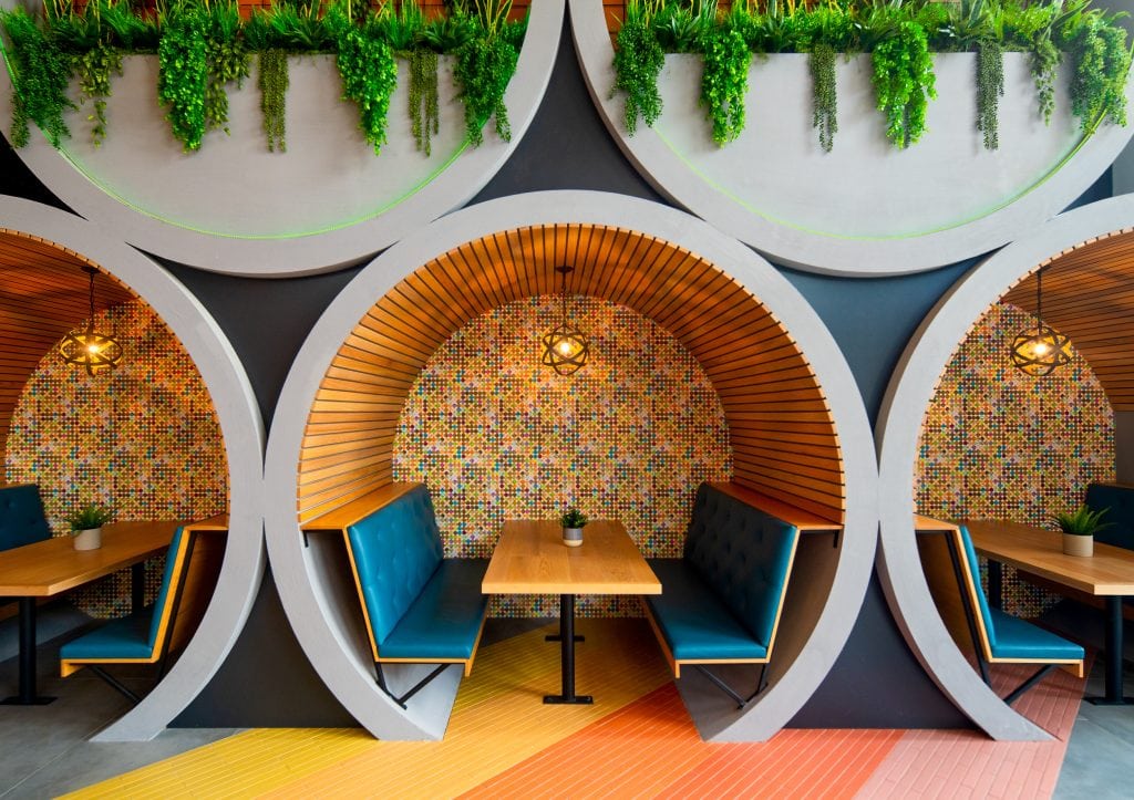 Broadstone Craft 9 Detail of barrel seating with colorful mosaic walls and greenery.