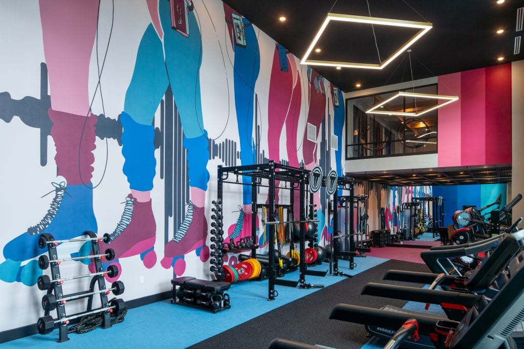 Broadstone Craft 10 Fitness center featuring 80s-inspired wall art and modern equipment.
