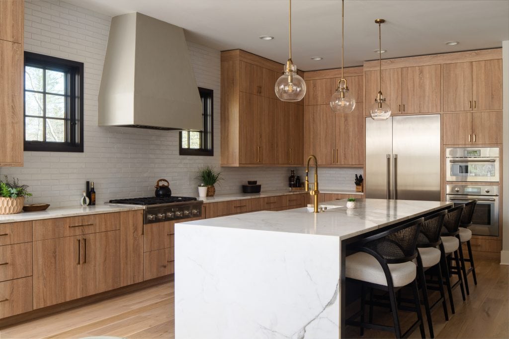 Flowering Vine 3 Light wood kitchen cabinets with quartz countertops and pendant lighting.