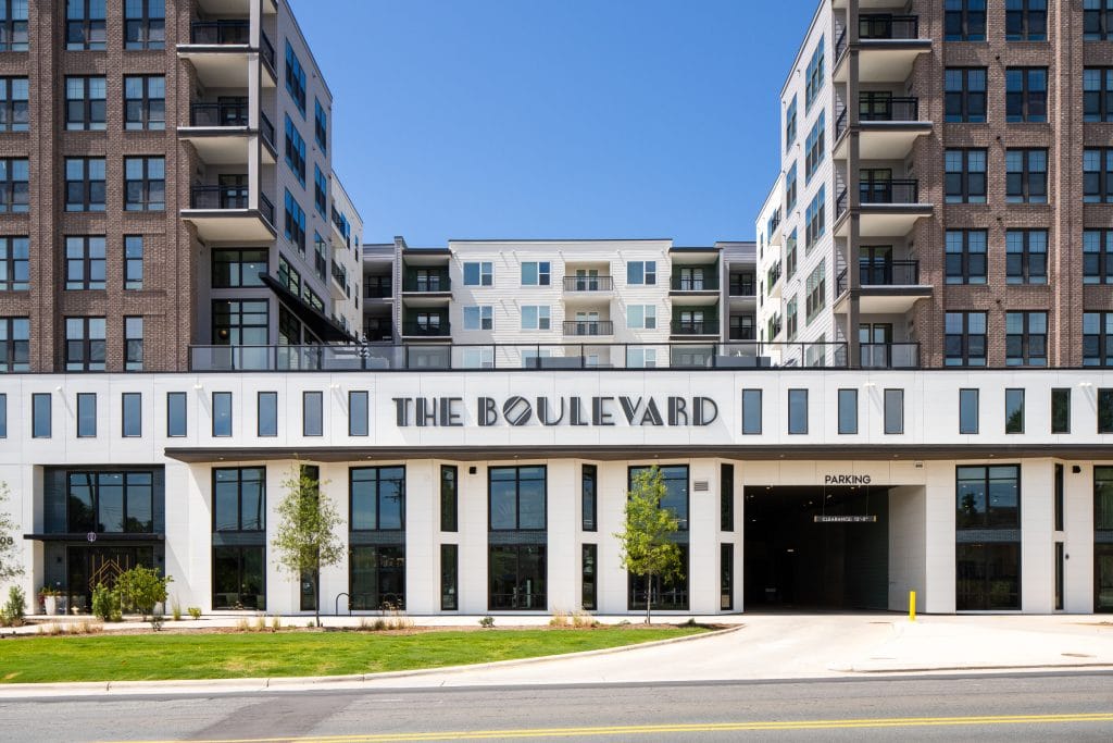 THE BOULEVARD 1 Residential building exterior with modern balconies, signage, and decorative landscaping.