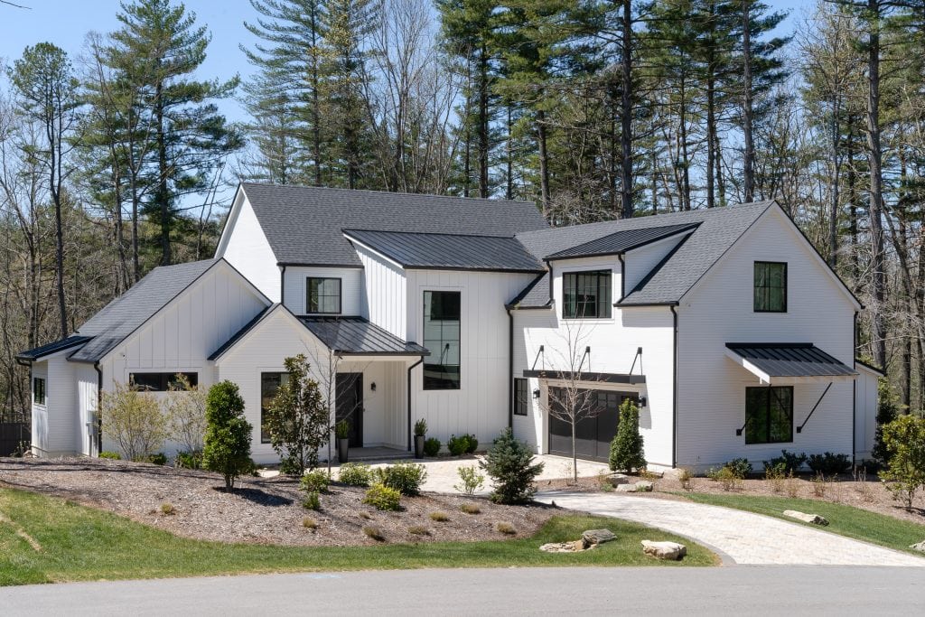 Flowering Vine 13 Exterior of a white modern farmhouse with a landscaped front yard.
