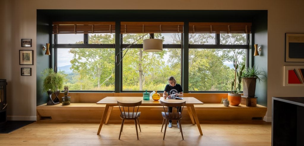 Dining space with large picture windows and natural greenery outside.