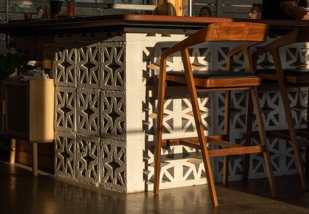 Golden Pony 11 Close-up of bar counter with decorative brickwork and wooden barstool.