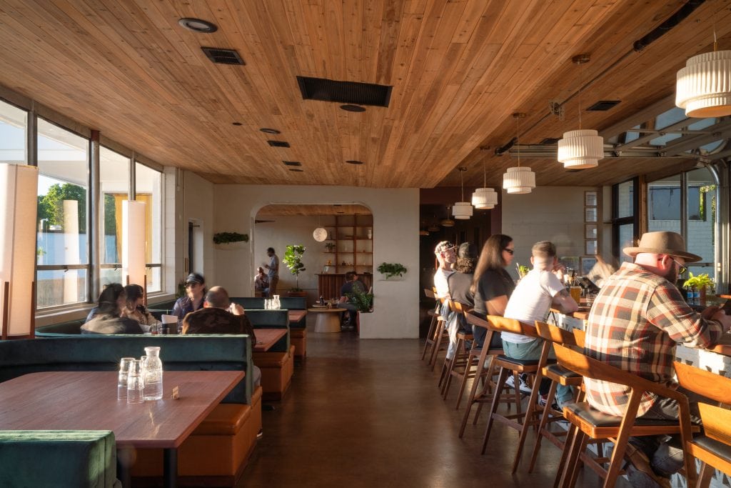 Golden Pony 14 Guests seated at a cocktail bar with modern pendant lighting and wooden finishes.