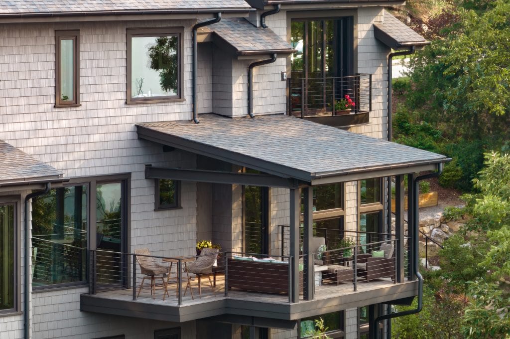 Laketown 2 Contemporary home with glass railing balcony and shaded outdoor seating.