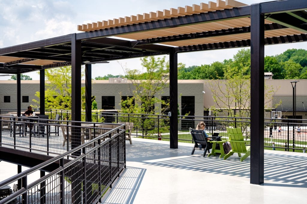 Long Hollow 12 Outdoor terrace with metal pergola, seating areas, and lush greenery in the background