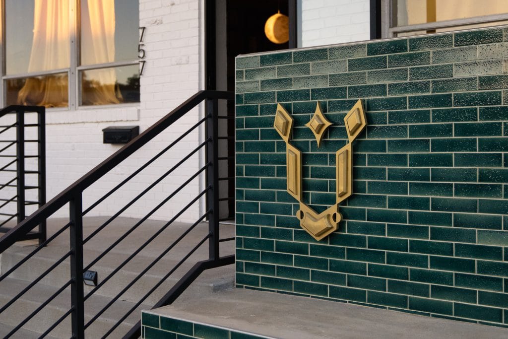 Golden Pony 19 Green-tiled exterior wall featuring a golden geometric logo.