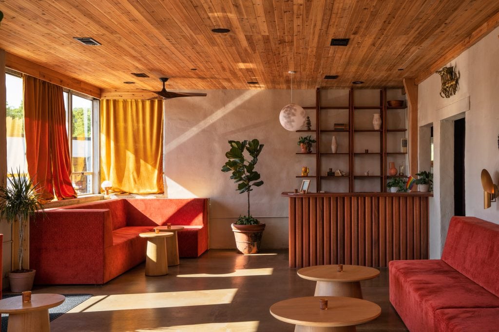 Golden Pony 1 Lounge seating area with red velvet booths and wooden tables bathed in warm evening light.