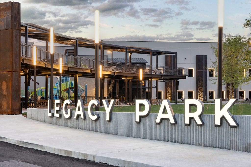 Long Hollow 2 Brightly lit "Legacy Park" sign with modern outdoor seating and lighting design.