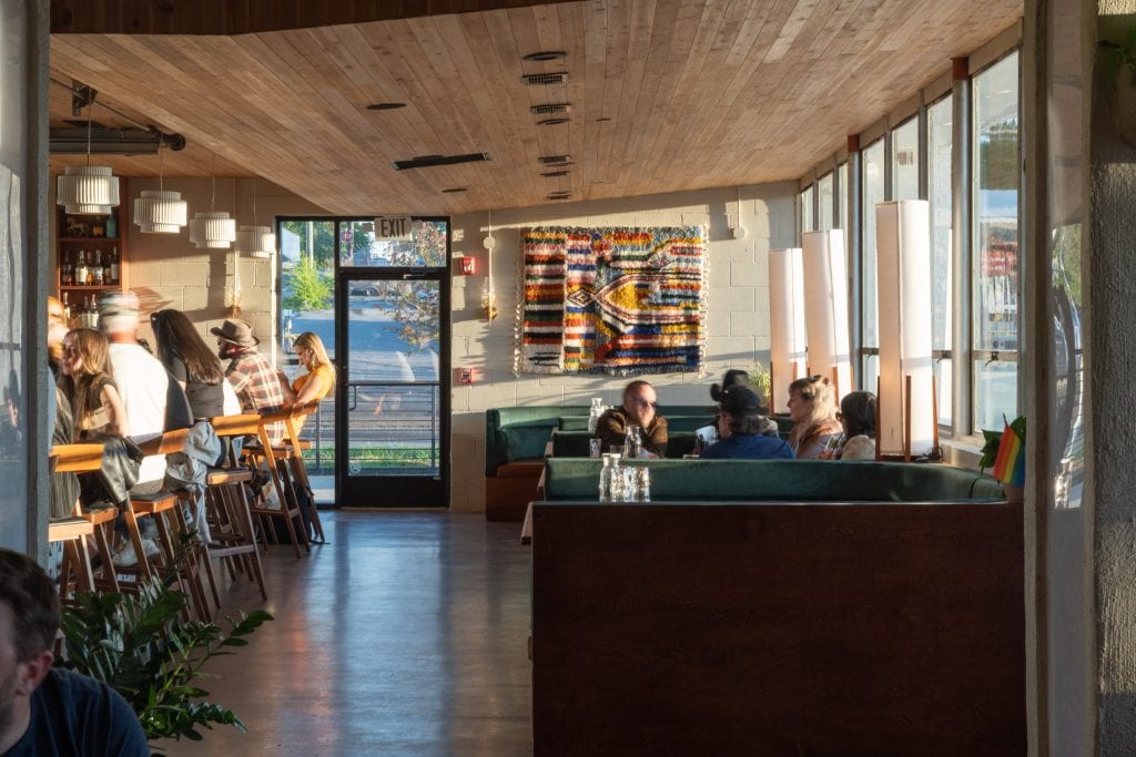 Golden Pony 13 Interior view of a stylish cocktail bar with a woven textile wall feature and warm lighting.
