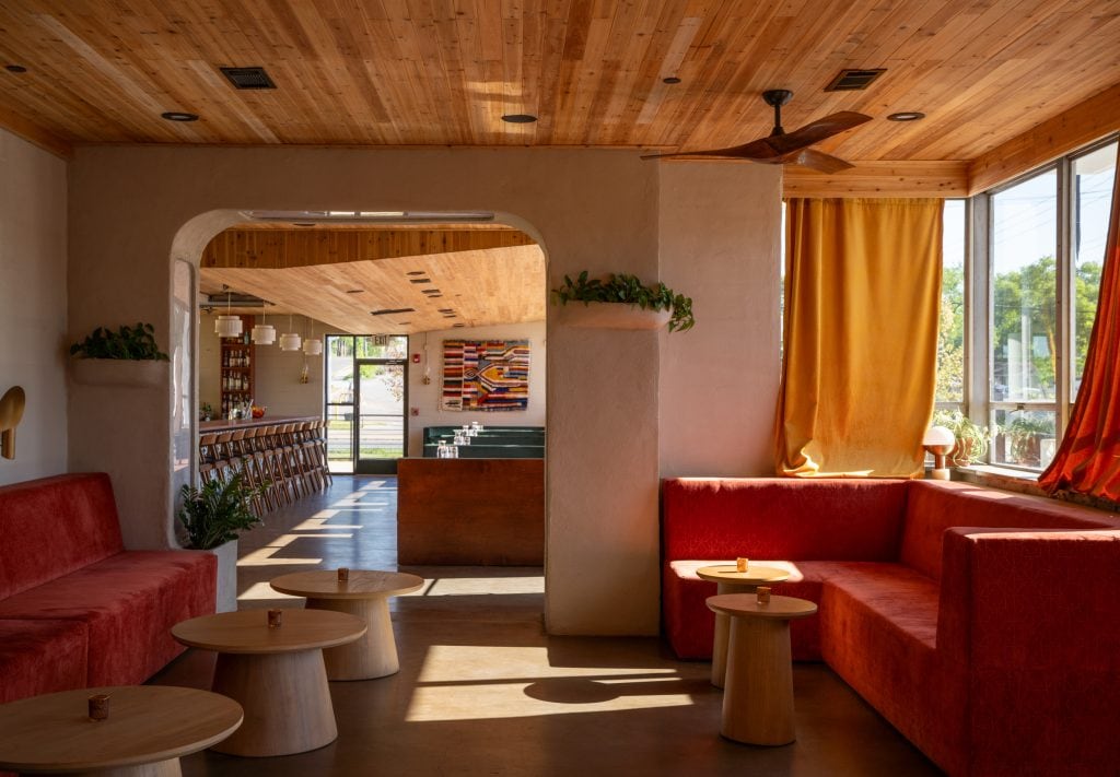Golden Pony 9 Lounge area featuring an open archway leading to the bar, mid-century furniture, and warm lighting.