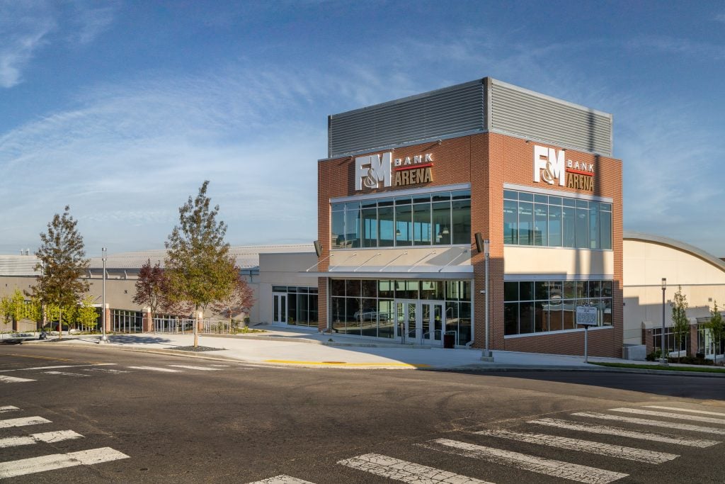 FM Bank Arena 3 Arenas’ main entryway featuring reflective glass panels and brick accents.