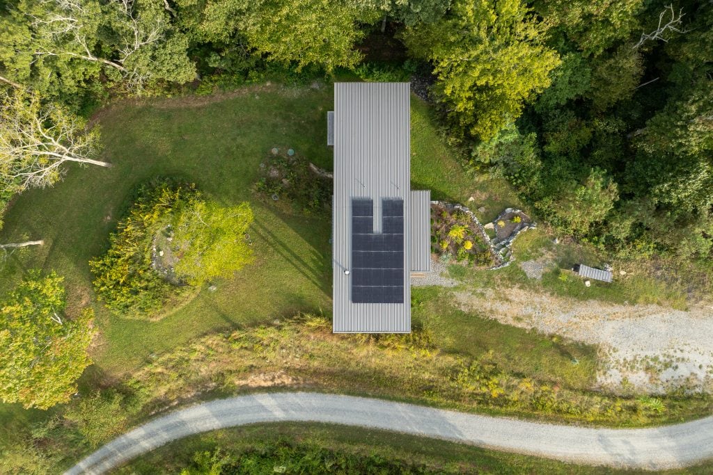 Freedom Cove 12 Aerial view of a modern home with solar panels surrounded by lush greenery.