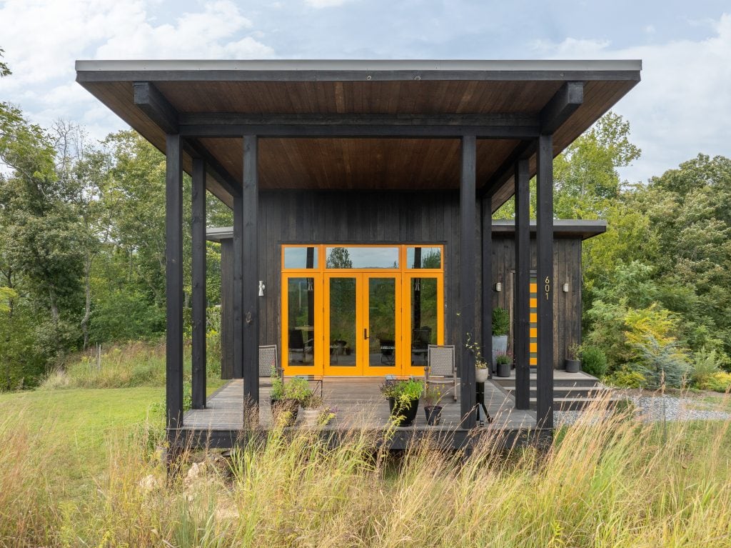 Freedom Cove 10 Black wood home exterior with a bright yellow door entrance.