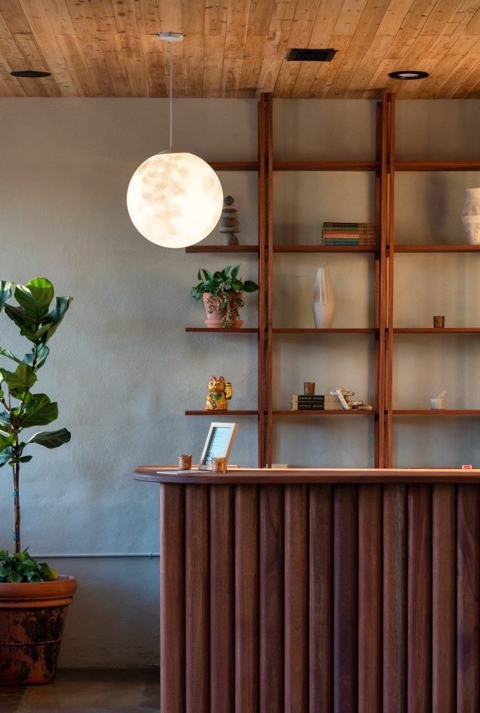 Golden Pony 4 Reception desk with a glowing moon pendant light and wooden shelving with decor.
