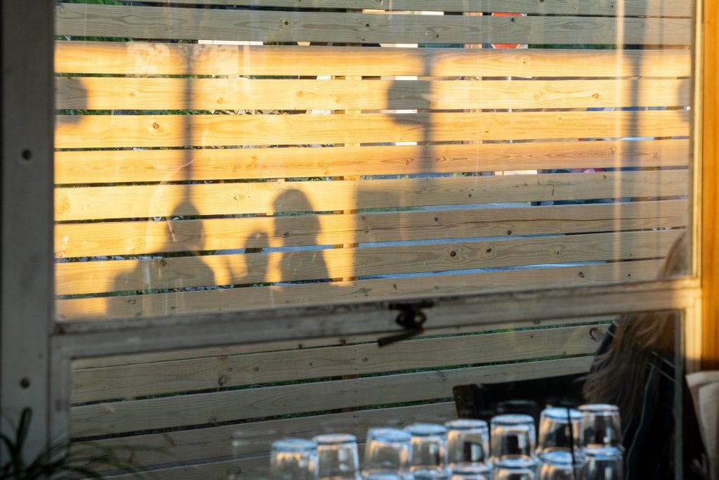 Golden Pony 18 Shadows of guests cast onto a wooden slatted wall at sunset.