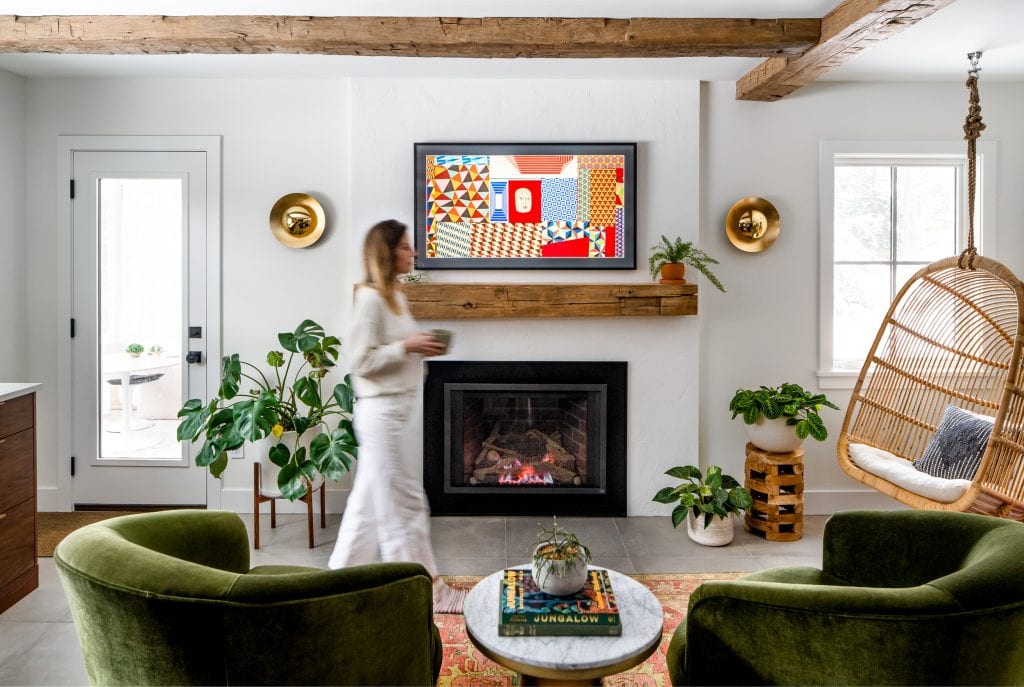 MINOR PARK MODERN 5 A cozy living room with green velvet chairs, a fireplace, and rustic wood beams.