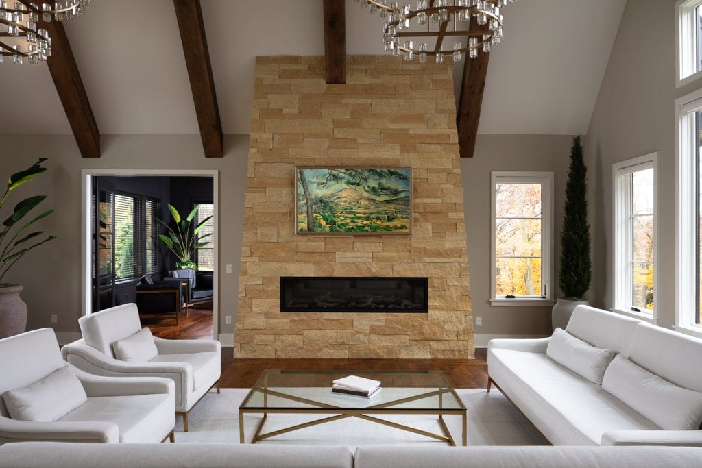 Marie 5 Modern living room with a floor-to-ceiling stone fireplace, neutral tones, and natural light.